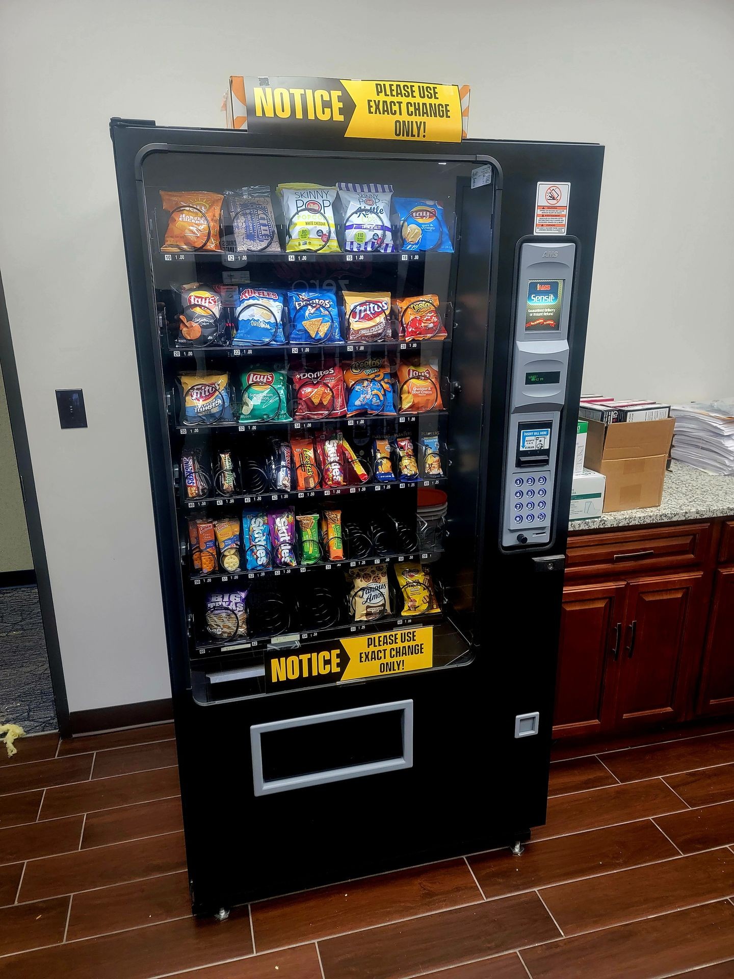 Vending machine stocked with snacks and a sign reading 'Please use exact change only.'